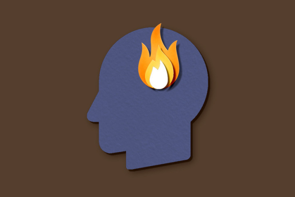 A dark blue paper head with orange, yellow, white cut-out flames inside against a brown background; concept is burnout 